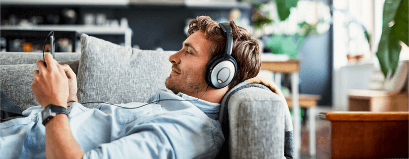 Homem ouvindo Podcast deitado no sofá durante a quarentena